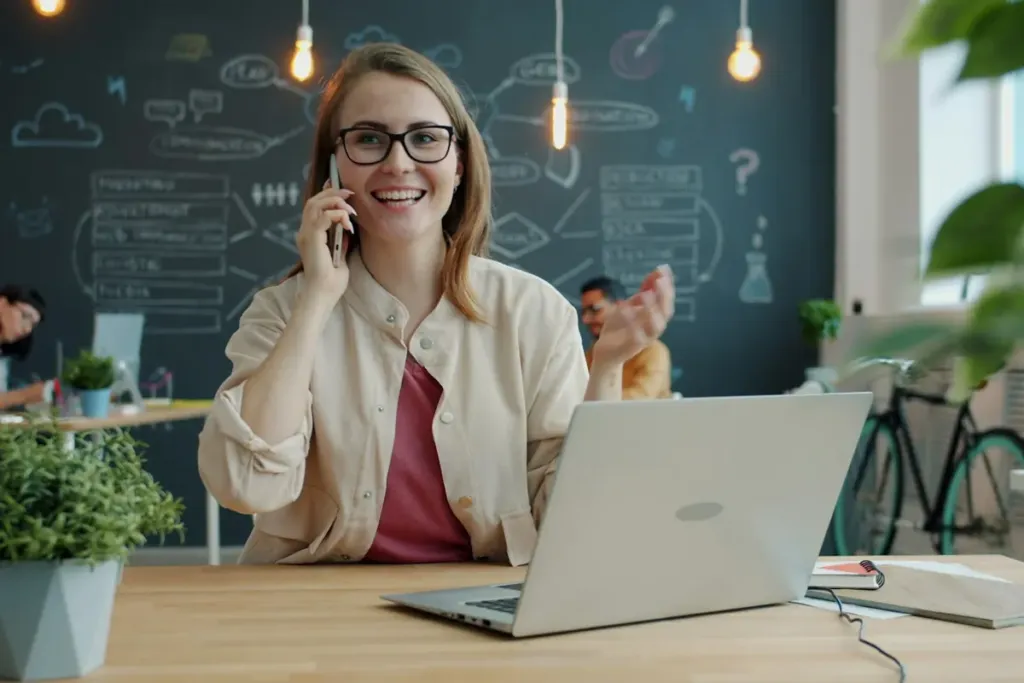 Una persona sorridente al telefono davanti al computer