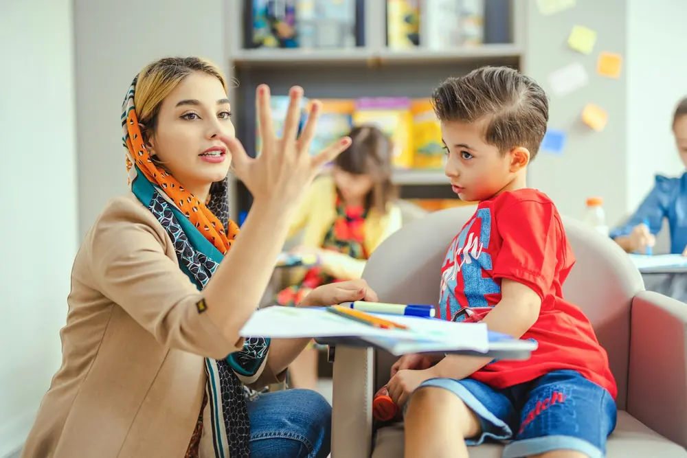 Un'educatrice comunica con un bambino aiutandosi con i gesti